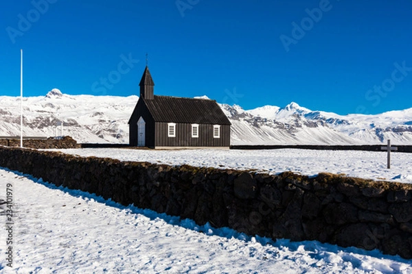 Fototapeta Budakirkja or better known as The Black Church view with blue sky during winter snow, Iceland
