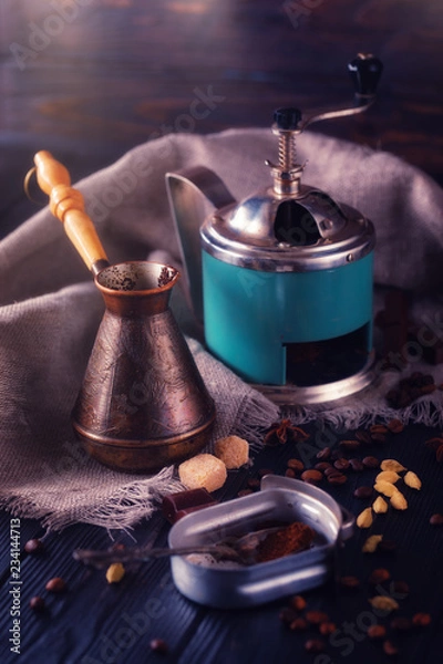 Obraz Close-up shot of vintage hand-operated old coffee grinder, roasted beans, chocolate, badyan, cardamom and cezve on a rustic wooden table.