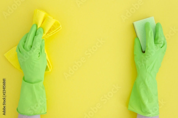 Fototapeta two Hands in green cleaning rubber glove with sponge isolated on yellow background.