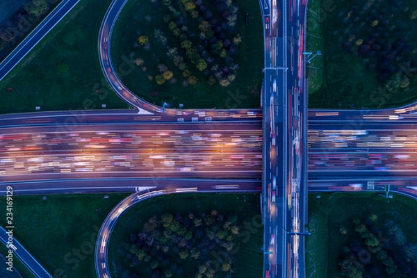 Fototapeta Highway junction seen from above at night with light trails of passing cars