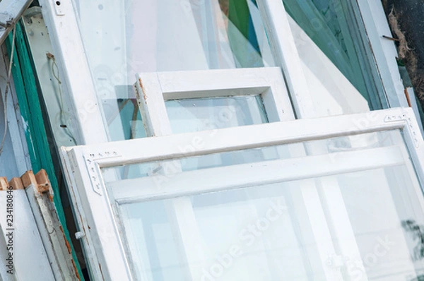 Fototapeta Many different construction debris from old wooden window frames  together with glass and white paint piled. Concept of replacement of old wooden window frames with new ones.