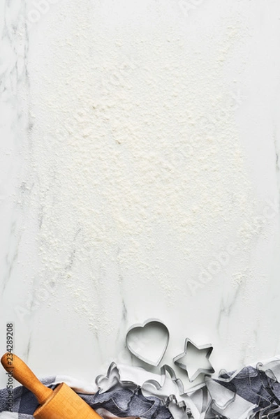 Fototapeta Baking background for baking Christmas cookies with cutters and rolling pin on white marble table with flour. Top view, copy space for text.