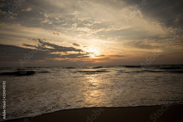 Fototapeta Sunset at seashore. Waves is coming.