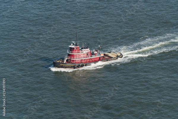 Obraz Aerial view of a New York City harbor tug boat sailing through water to assist large container and tank ships into port