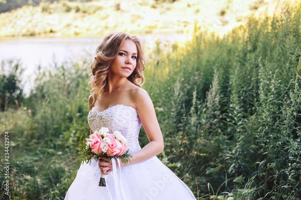 Fototapeta Photo of the bride in nature with a beautiful bouquet of flowers