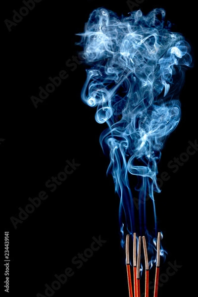 Obraz Closeup of calmly burning incense sticks with blue fume on black background
