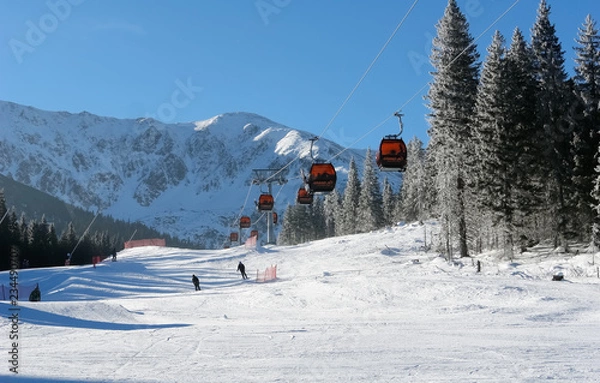 Fototapeta Cableway cabins and skiers on a sunny day on the slopes of the Jasna ski resort.