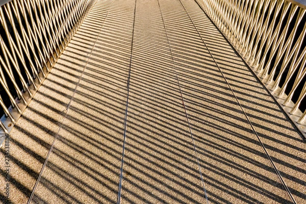 Fototapeta shadows of a handrail on a footbridge making abstract patterns in London England