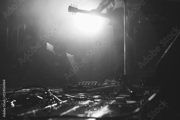 Fototapeta Rainy stage flore with the guitar gear and microphone and guitarist at background in a backlights