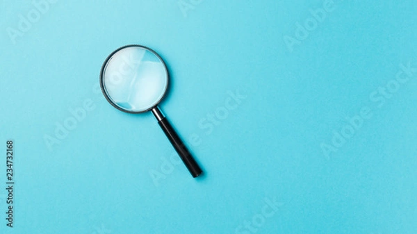 Fototapeta Magnifying glass on pastel background. Top view. Flat lay. Copy space. Minimal creative concept. Blue background in pastel colours