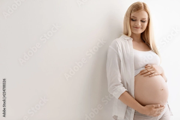 Fototapeta Portrait of beautiful pregnant woman on light background. Space for text
