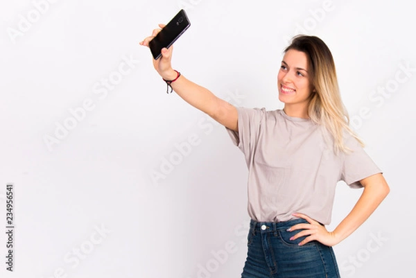 Fototapeta Girl on white with cell phone smiling using  internet social media concept 