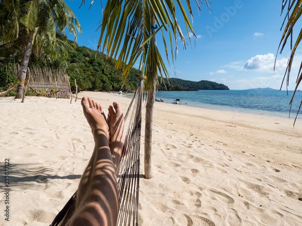 Fototapeta Man relaxing in the hammock on tropical beach with palm-trees, hot sunny day. Philippines, November, 2018