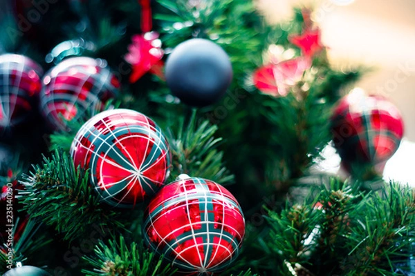 Fototapeta Closeup of red bauble hanging from a decorated Christmas tree. Happy new year concept.