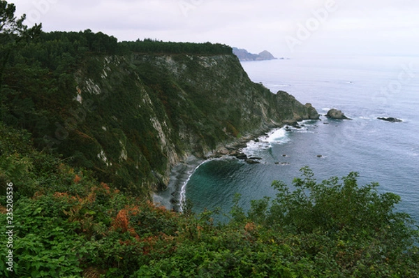 Obraz Wonderful view to the sea waves and cliffs surrounded by green shrubs near Cudillero in Spain