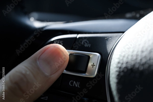 Fototapeta A man hand finger operating the Auto Cruise function in a modern car