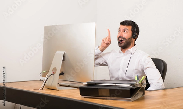 Fototapeta Telemarketer man in a office intending to realizes the solution while lifting a finger up