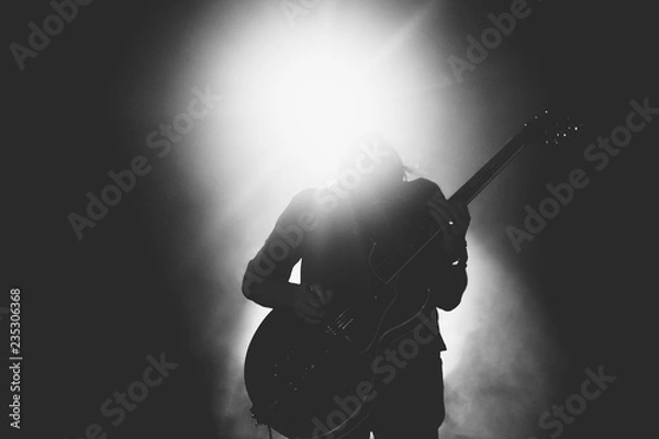 Obraz Black and white picture of guitarist silhouette playing solo in bright backlights 