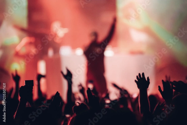 Fototapeta Silhouette of a singer on a stage singing to the crowd with the hands raised up