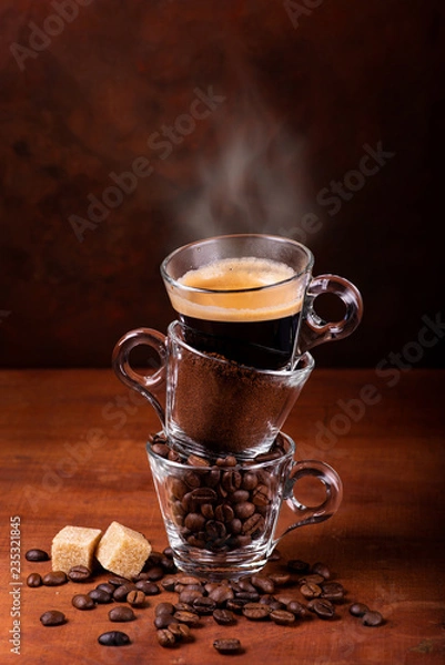Fototapeta glass cups, in sequence vertically, with coffee beans, ground, and steaming drink. still life