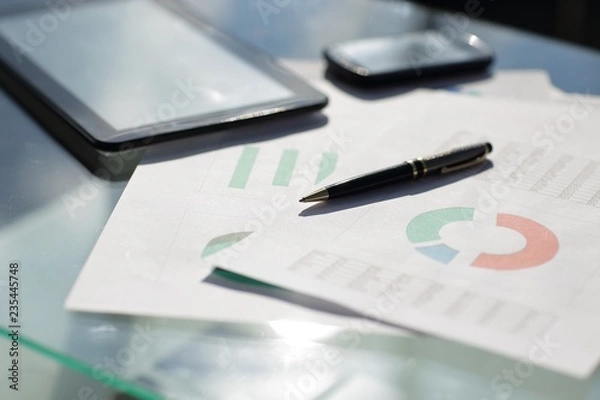 Fototapeta Financial paper charts and graphs on the table