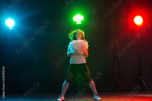 Fototapeta Cheerleading happy girl dancing on dark background