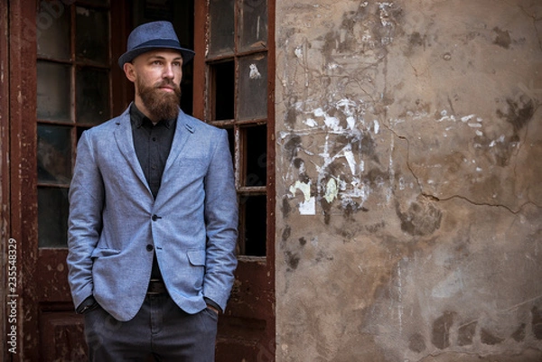 Fototapeta stylish man with a beard in a hat on the street