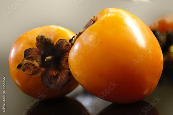 Fototapeta Two ripe yellow persimmon lying on the table