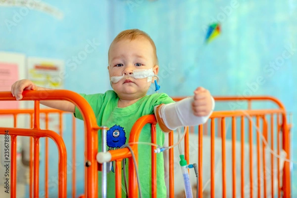 Obraz little boy in hospital bed with iv infusions and oxigen