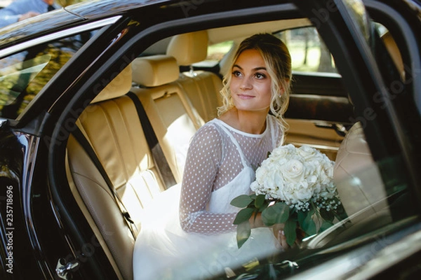 Obraz A bride takes pictures in the black car.