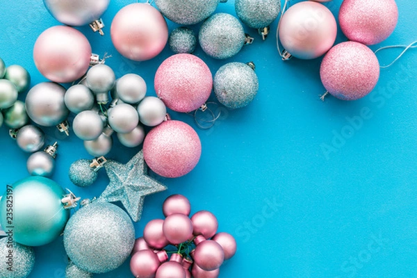 Fototapeta Christmas and New Year symbols. Toys for festive tree. Blue and pink balls and stars on blue background top view copy space border