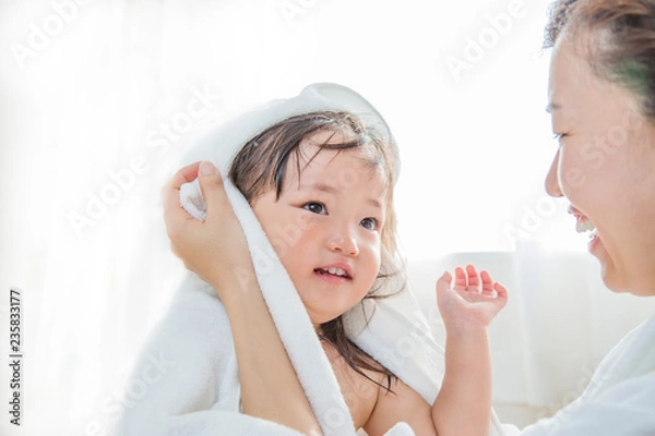 Fototapeta 湯上りの幼い女の子をバスタオルで拭くお母さん。育児、清潔、健康、親子イメージ