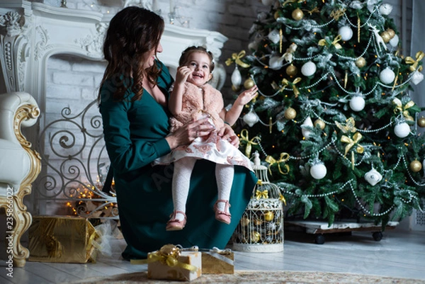 Fototapeta Merry Christmas and happy holidays. Mother and daughter having fun near the Christmas tree with gifts