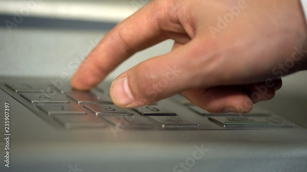 Obraz Male hand using ATM, inserting unique personal code and pressing buttons