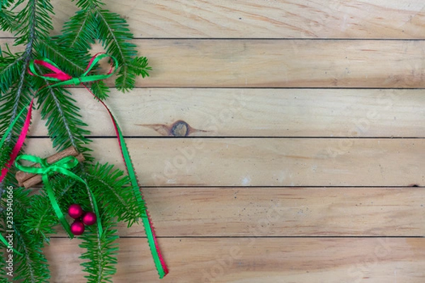 Obraz Greenery with  a ribbon bow, cinnamon sticks, and red berries  along left side border with copy space