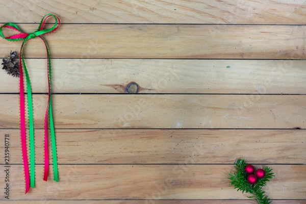 Obraz A green and red ribbon bow with cedar cones and red berries and  on greenery with copy space