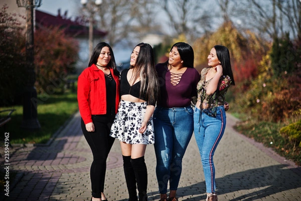 Fototapeta Group of four happy and pretty latino girls from Ecuador posed at street.