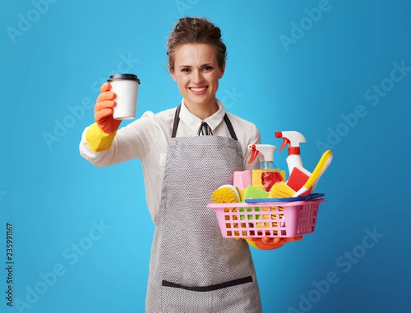 Obraz housemaid with a basket with cleansers and brushes giving a coff