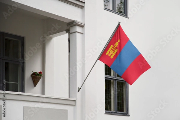 Fototapeta Mongolia flag hanging on a pole in front of the house. National flag waving on a home displaying on a pole on a front door of a building and raised at a full staff.