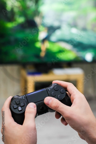 Fototapeta Close up view of man's hands with controller for playing video game