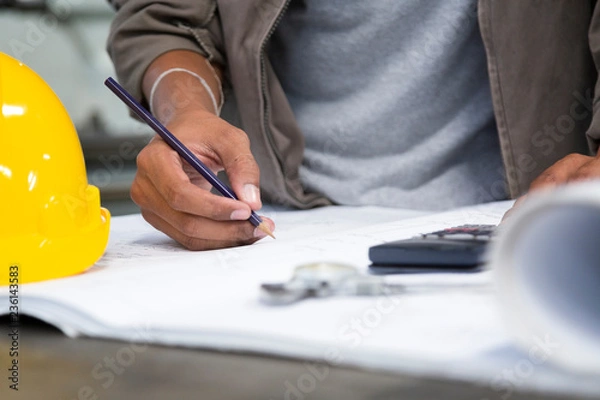 Fototapeta Engineer man writting drawings inspection and calculation in office .Engineering tools and construction concept. architect and Business concept.
