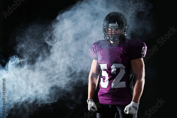Fototapeta American football player wearing uniform on dark background. Space for text
