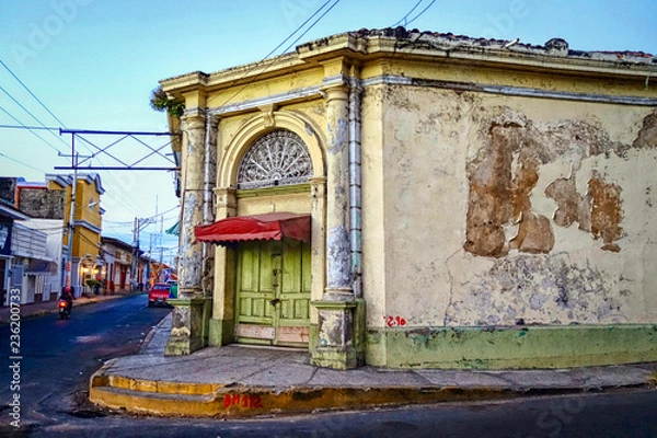 Fototapeta An old, weathered building with a green door and flaking paint on a corner in the city of Leon in northern Nicaragua