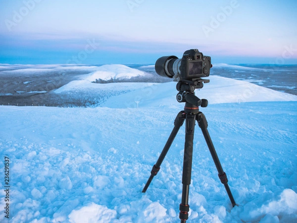 Fototapeta DLSR digital camera on tripod in nature with snow
