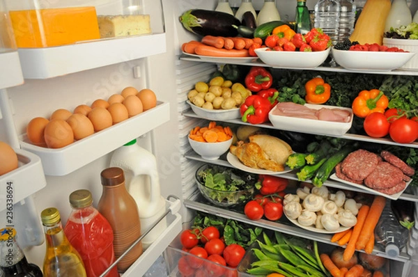 Fototapeta VIEW INSIDE REFRIGERATOR WITH SHELVES FILLED WITH FRESH FOOD