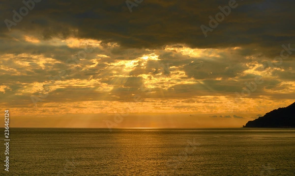 Fototapeta beautiful golden sunset over sea with clouds, mountain in backlight