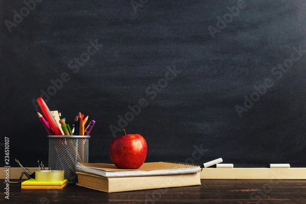 Fototapeta Teacher's desk with writing materials, a book and an apple, a blank for text or a background for a school theme. Copy space.