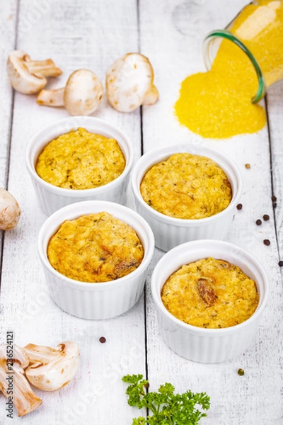 Obraz Polenta with mushrooms in white ramekin bowls on wooden rustic table. Close up