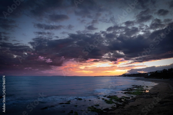 Fototapeta Sunset on the edge of the sea. The sky is illuminated with warm colors.