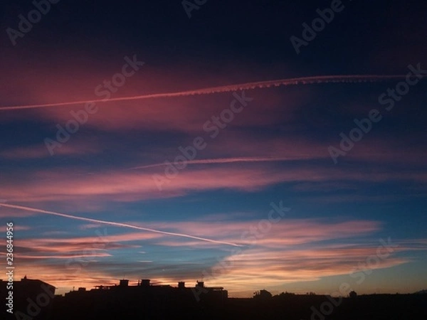 Fototapeta City skyline after sunset with colorful contrails